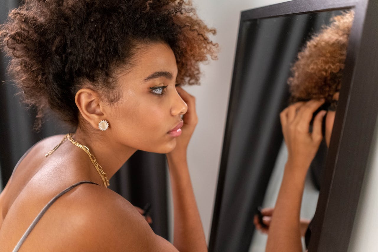 Contact Close-up of a woman applying makeup while reflecting in a mirror indoors.